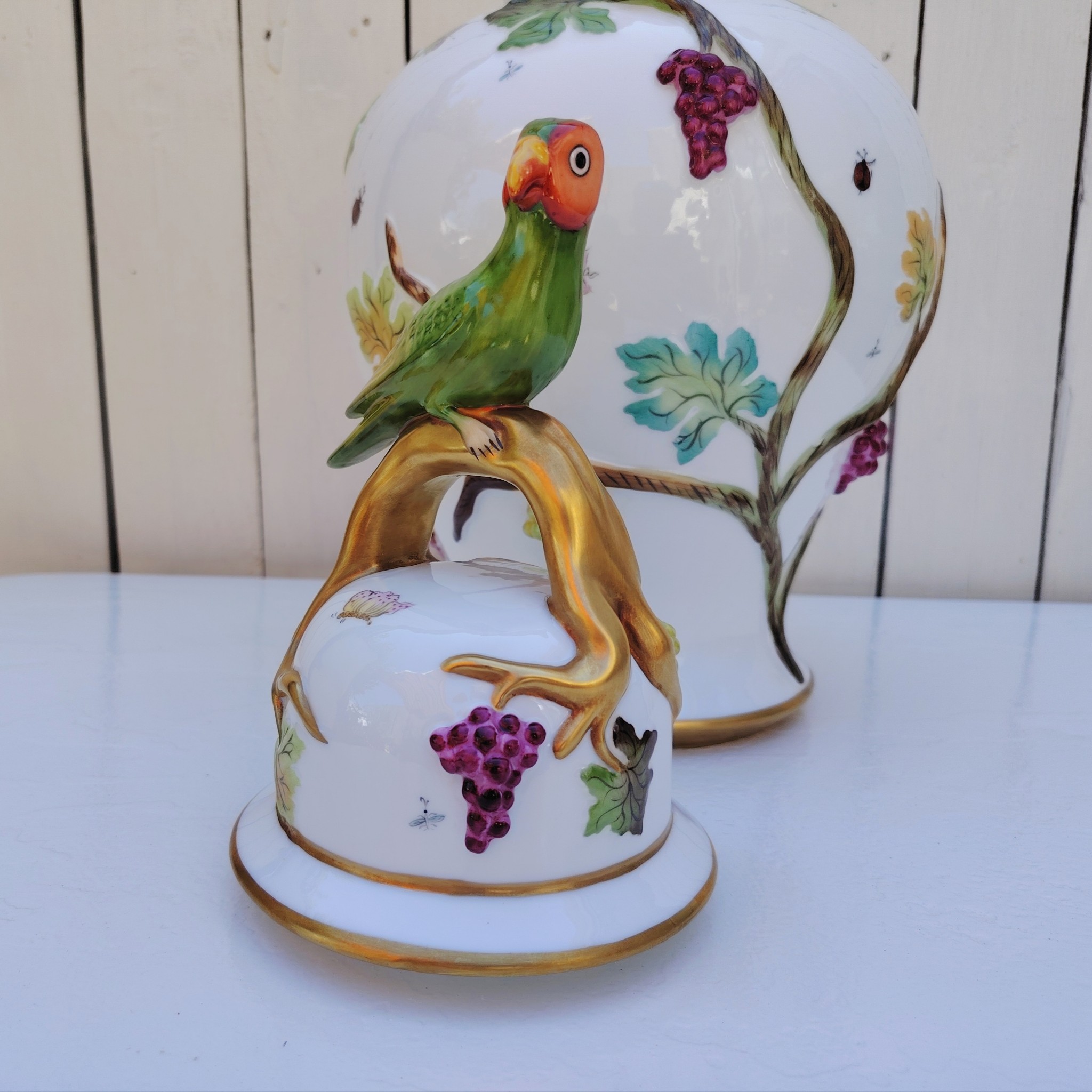 Grand pot couvert en porcelaine portugaise Pac. Orné de vignes et grappes de raisins en relief, et de papillons et coccinelles peints. Liseré doré, poignée du couvercle représentant une branche dorée surhaussé d'un perroquet. Très belle facture. Excellent état.  Hauteur avec couvercle : ~47 cm