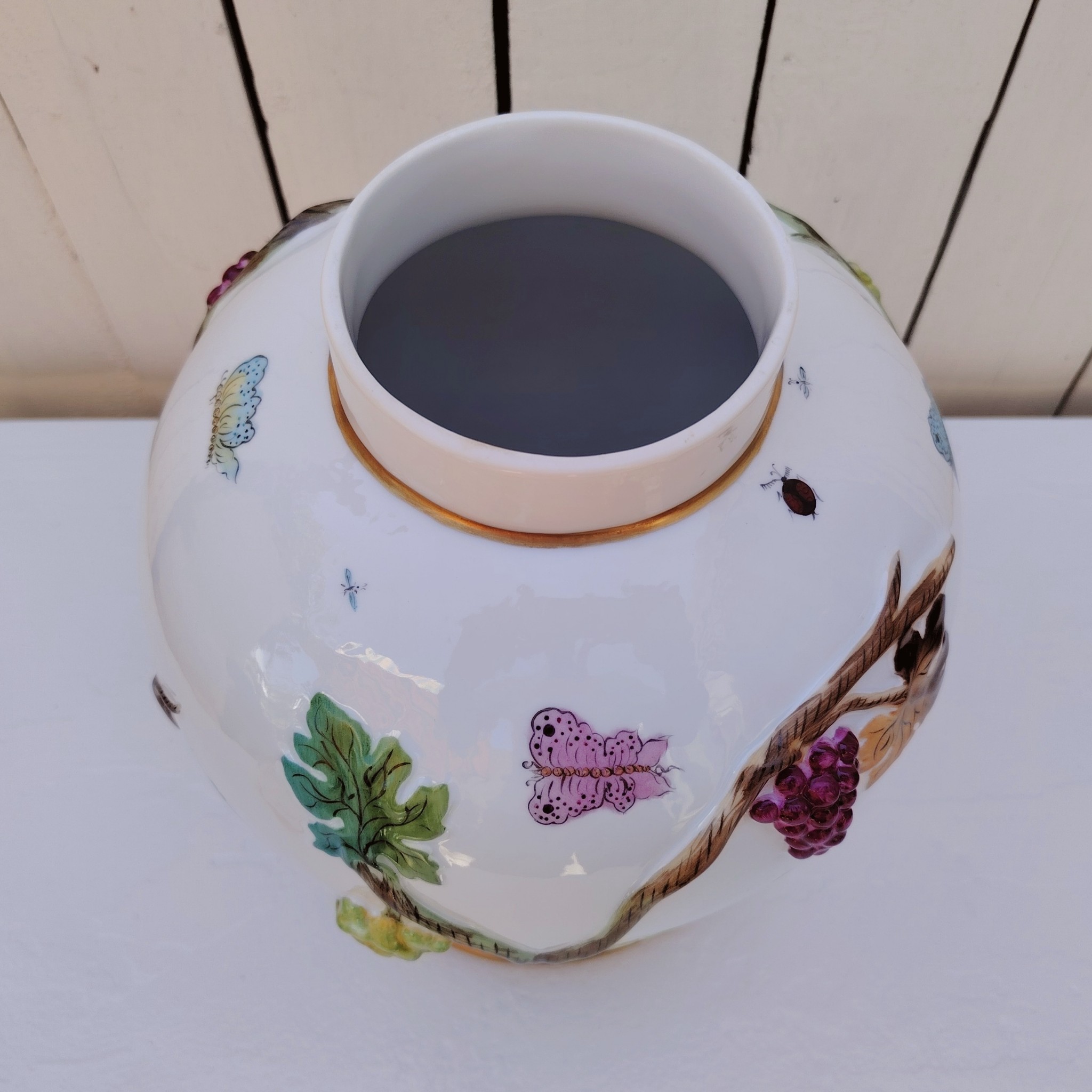 Grand pot couvert en porcelaine portugaise Pac. Orné de vignes et grappes de raisins en relief, et de papillons et coccinelles peints. Liseré doré, poignée du couvercle représentant une branche dorée surhaussé d'un perroquet. Très belle facture. Excellent état.  Hauteur avec couvercle : ~47 cm