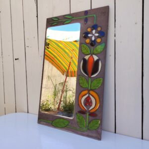 Miroir à poser en pierre de lave avec fleurs colorées émaillées, traces sur le miroir probablement la colle que l'on voit au travers. Très bel objet déco. Bon état général. Dimensions : 50 x 30 cm
