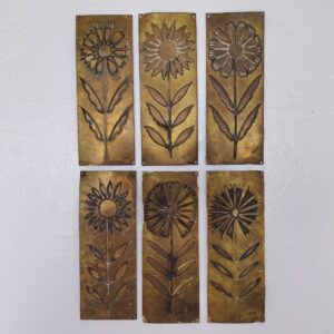 Six plaques de propreté en laiton embouti, à décor de fleurs. Elles sont un peu tordues, et les certains coins repliés. Traces de vert-de-gris et traces d'usage Bon état général Dimensions : 16 x 6 cm