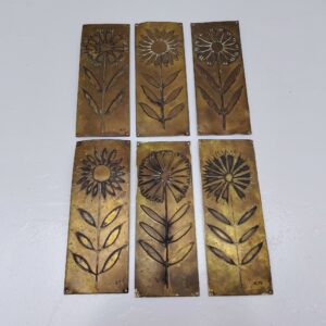 Six plaques de propreté en laiton embouti, à décor de fleurs. Elles sont un peu tordues, et les certains coins repliés. Traces de vert-de-gris et traces d'usage Bon état général Dimensions : 16 x 6 cm