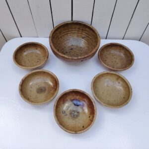 Service en grès pyrité, comprenant un saladier et 5 bols ou petites assiettes creuses. très bon état Hauteur saladier : 12 cm diamètre saladier : 23 cm Hauteur bols/assiettes : 5,5 cm diamètre : 16 cm