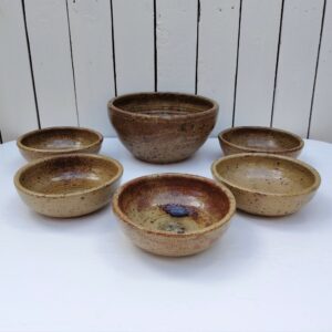 Service en grès pyrité, comprenant un saladier et 5 bols ou petites assiettes creuses. très bon état Hauteur saladier : 12 cm diamètre saladier : 23 cm Hauteur bols/assiettes : 5,5 cm diamètre : 16 cm