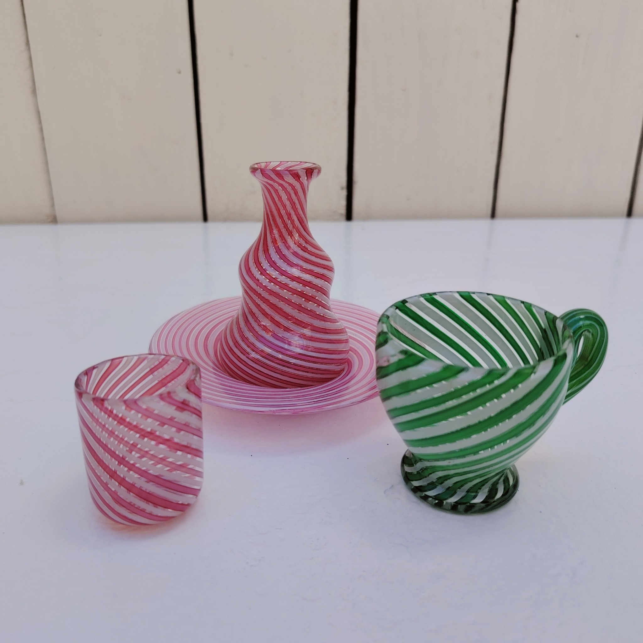 Lot dînette e en verre soufflé de Murano, Composé d'une petite assiette, un gobelet, une cruche de couleur rose et une tasse de couleur verte Excellent état Hauteur gobelet : 3,5 cm diamètre : 3 cm Hauteur cruche : 7 cm Hauteur tasse : 5 cm diamètre : 4,5 cm Diamètre assiette : 9 cm