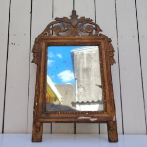 Ancien miroir en bois et stuc doré, de style Louis XVI, fin XVIIIéme début XIXéme. Fronton à enroulement de feuillage orné d'un coeur en son centre. Manque une partie du fronton, des éclats et maque de dorure. Tain terni et taché. Dans son jus Dimensions : 54 x 33 x 4 cm