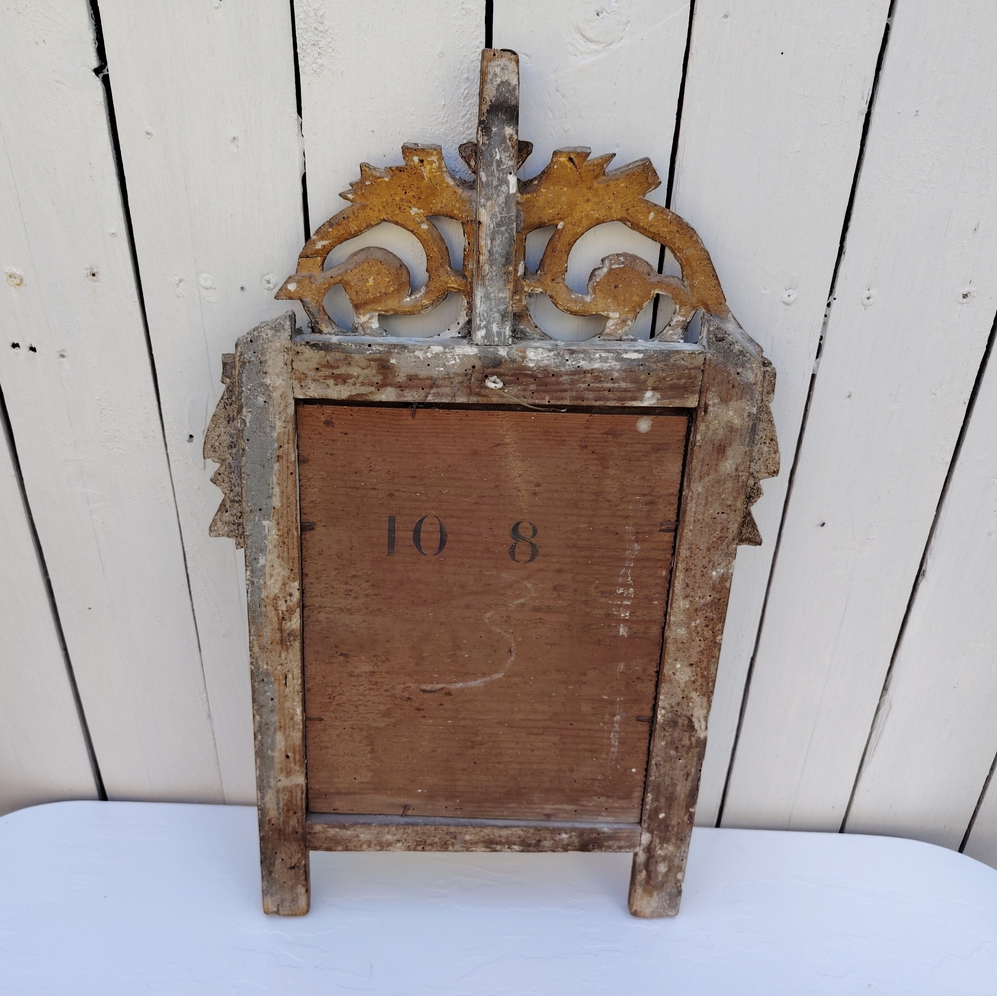 Ancien miroir en bois et stuc doré, de style Louis XVI, fin XVIIIéme début XIXéme. Fronton à enroulement de feuillage orné d'un coeur en son centre. Manque une partie du fronton, des éclats et maque de dorure. Tain terni et taché. Dans son jus Dimensions : 54 x 33 x 4 cm