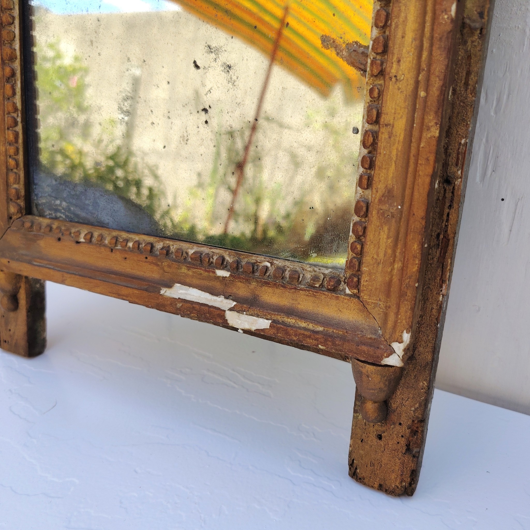 Ancien miroir en bois et stuc doré, de style Louis XVI, fin XVIIIéme début XIXéme. Fronton à enroulement de feuillage orné d'un coeur en son centre. Manque une partie du fronton, des éclats et maque de dorure. Tain terni et taché. Dans son jus Dimensions : 54 x 33 x 4 cm