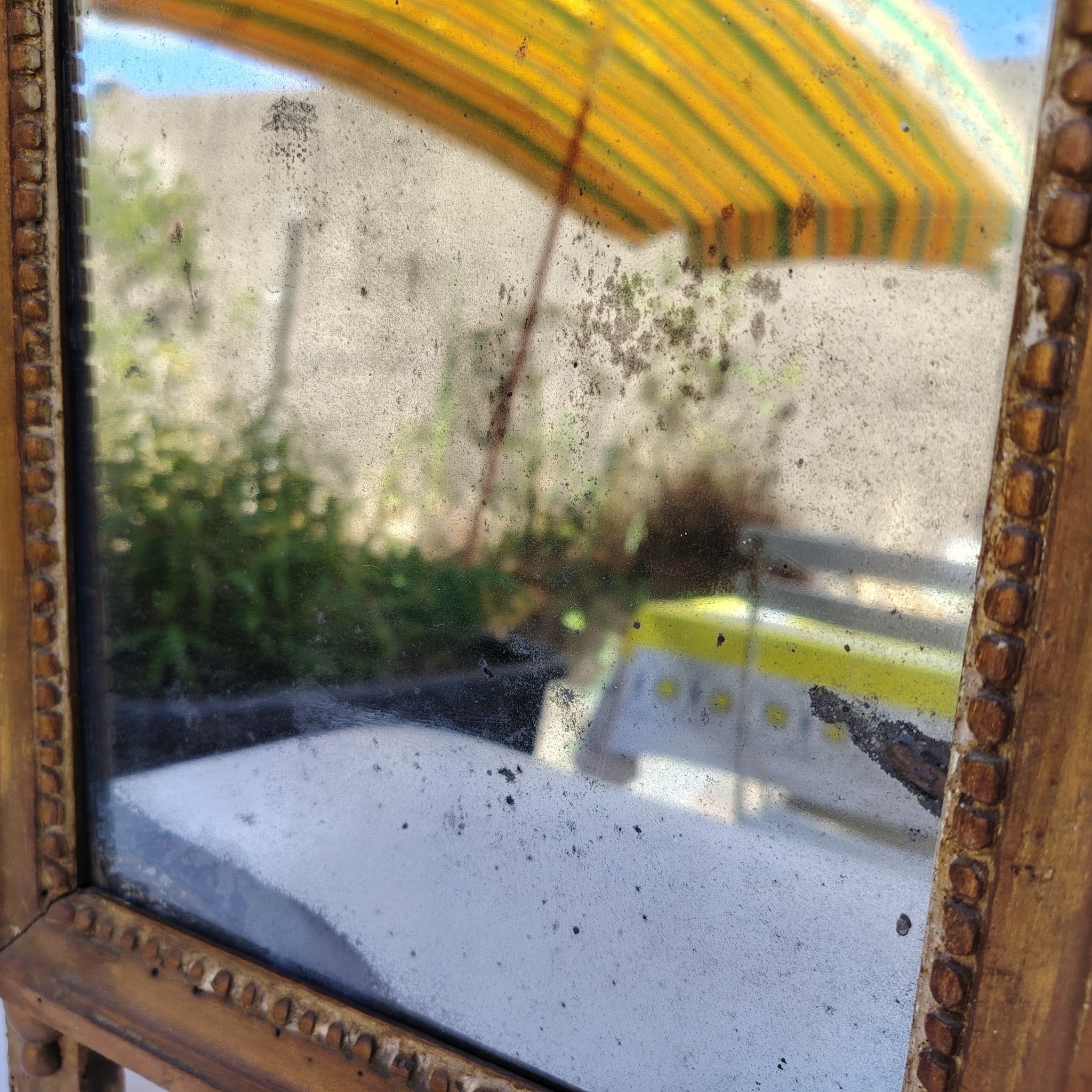 Ancien miroir en bois et stuc doré, de style Louis XVI, fin XVIIIéme début XIXéme. Fronton à enroulement de feuillage orné d'un coeur en son centre. Manque une partie du fronton, des éclats et maque de dorure. Tain terni et taché. Dans son jus Dimensions : 54 x 33 x 4 cm
