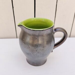 Pichet en céramique noire irisée sur l'extérieur et vert brillant sur l'intérieur en faïence. Petites égrenures au bec et au pied Bon état général Hauteur : 14,5  cm Diamètre : 9,5  cm