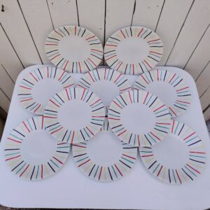 Lot de 10 assiettes plates en faïence de Longchamp, datant des années 50-60. Au décor de rayures colorées. Traces et rayures d'usage sans gravité, un féle sur une assiette. Bon état général. Diamètre : 23,5 cm