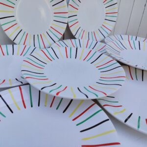 Lot de 10 assiettes plates en faïence de Longchamp, datant des années 50-60. Au décor de rayures colorées. Traces et rayures d'usage sans gravité, un féle sur une assiette. Bon état général. Diamètre : 23,5 cm