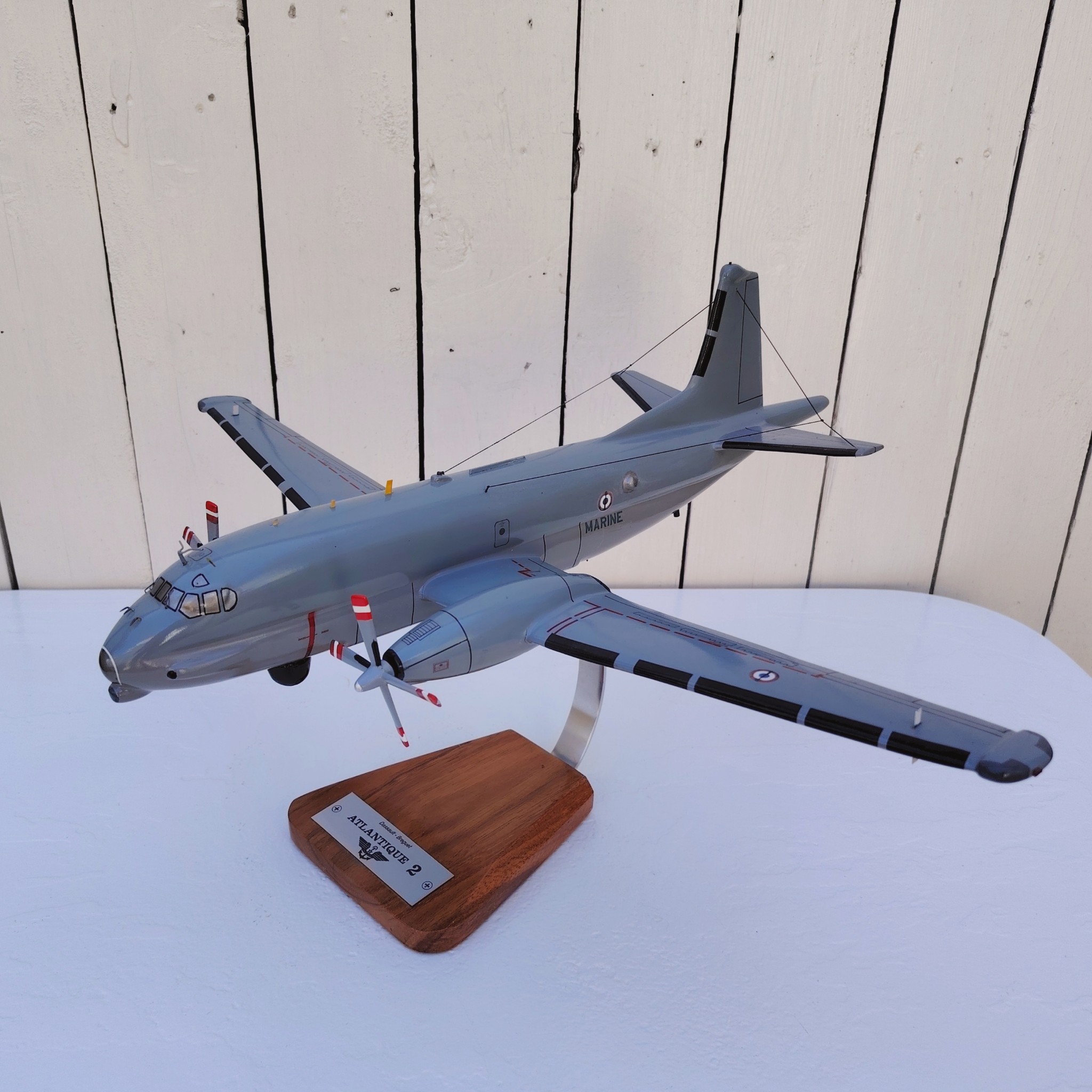 Maquette avion de la marine Française. Modèle: Atlantique 2 Réalisation en bois massif, sculptée et peinte à la main. Sur socle en Acacia vernis avec plaquette gravée. De la marque Pilot station Petites traces et rayures d'usage. Bon état général Dimensions : 45 x 50 x 27 cm