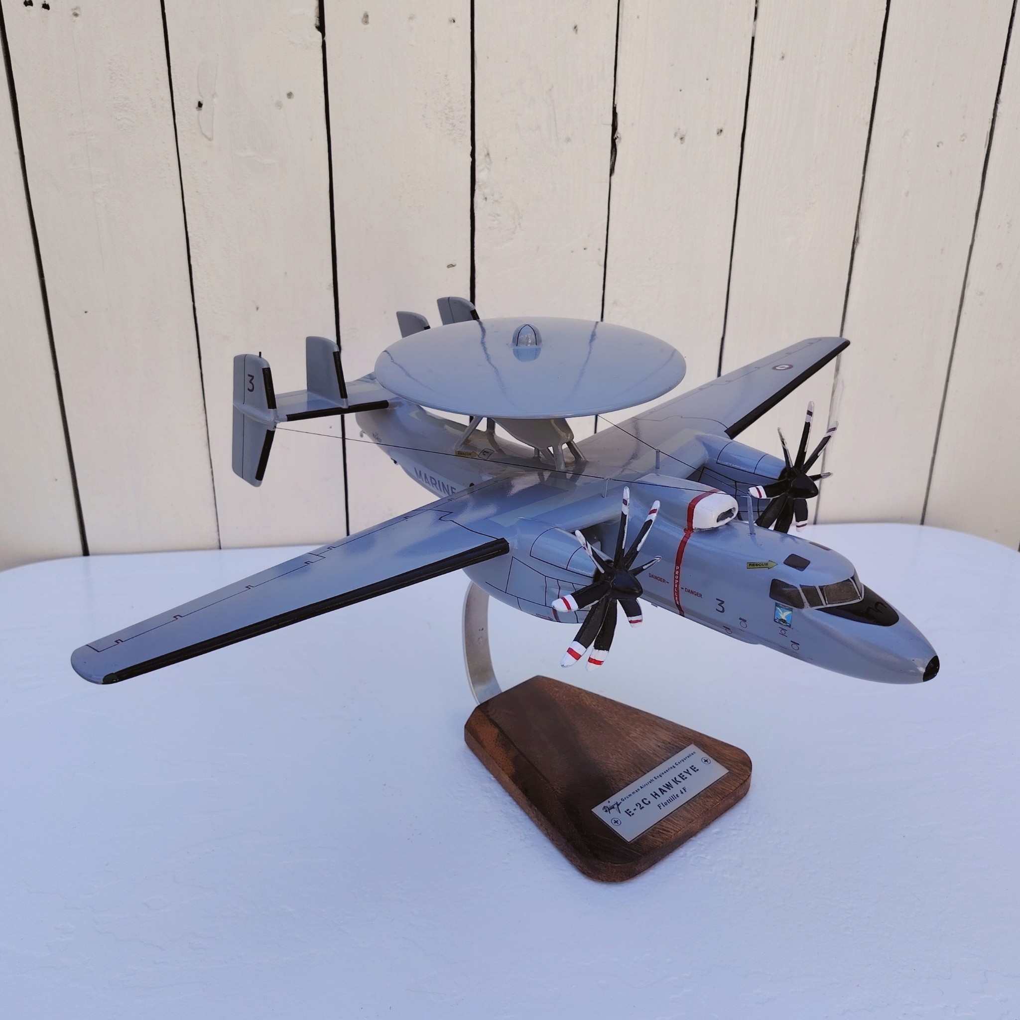 Maquette avion aux couleurs de la Flottille 4F de l'Aéronavale Française. Modèle: E2C-Hawkeye, Réalisation en bois massif, sculptée et peinte à la main. Sur socle en Acacia vernis avec plaquette gravée. De la marque Pilot station. Petites traces et rayures d'usage. Bon état général Dimensions : 37x49x 24 cm