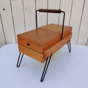 Ancienne boîte à couture étirable en bois datant des années 60. Piétement en métal noir. Petites traces et rayures d'usage.  bon état général. Hauteur : 33,5 cm Longueur dépliée : 60 cm Dimensions pliée : 35 x 20 cm