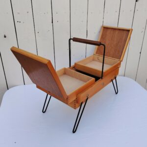 Ancienne boîte à couture étirable en bois datant des années 60. Piétement en métal noir. Petites traces et rayures d'usage.  bon état général. Hauteur : 33,5 cm Longueur dépliée : 60 cm Dimensions pliée : 35 x 20 cm