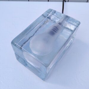 Lampe ampoule intitulée " Block lamp", fabriquée en suède créée par Harri Koskinen. Deux blocs de verre épais surperposés qui enferme une ampoule. Très bon état Dimensions : 16 x 10 x 10 cm
