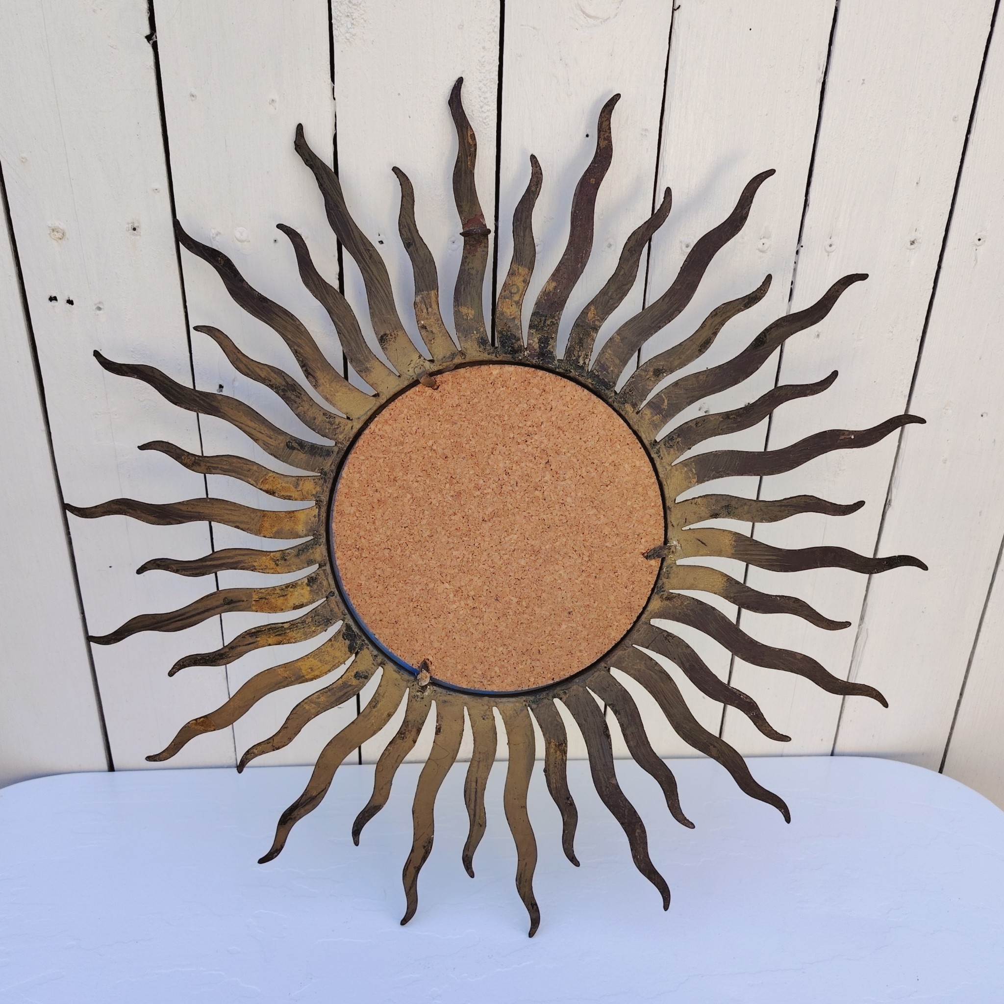 Miroir soleil, oeil de sorcière, en métal patiné doré datant des années 50. Miroir biseauté. Traces de corrosion et manques de dorures. Un point d'accroche sur l'arrière. Bon état général Diamètre total : 53,5 cm Diamètre miroir : 20,5 cm