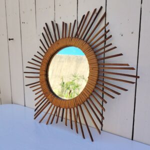 Miroir soleil en rotin datant des années 60. Traces de piqûres sur le miroir. Un point d'accroche sur l'arrière. Bon état général. Diamètre total : 42 cm Diamètre miroir : 17,5 cm