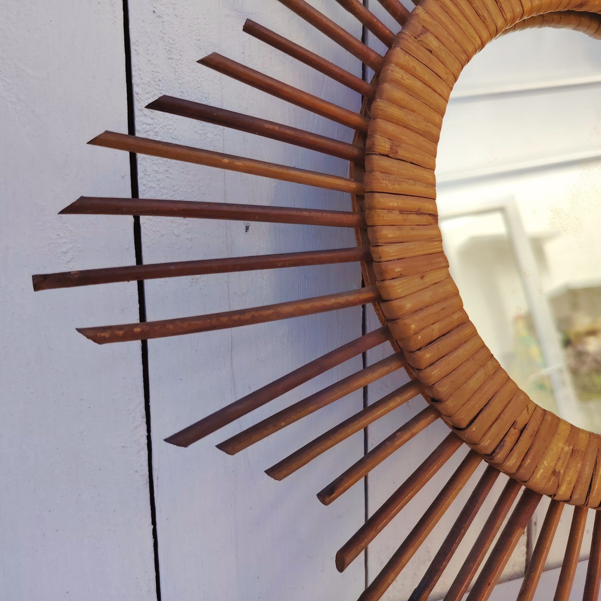  Miroir soleil en rotin datant des années 60.  Traces de  piqûres sur le miroir. Un point d'accroche sur l'arrière.  Bon état général. Diamètre total : 42  cm Diamètre miroir : 17,5 cm