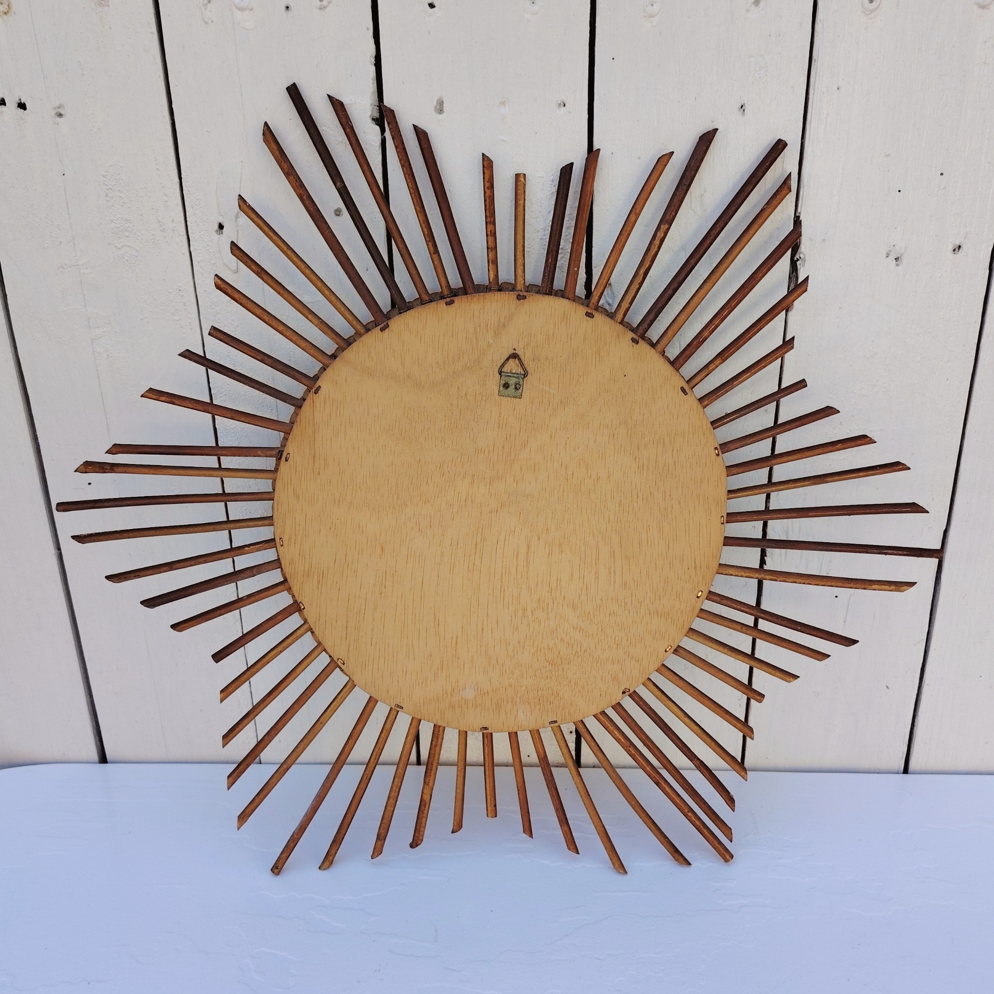 Miroir soleil en rotin datant des années 60.  Traces de  piqûres sur le miroir. Un point d'accroche sur l'arrière.  Bon état général. Diamètre total : 42  cm Diamètre miroir : 17,5 cm