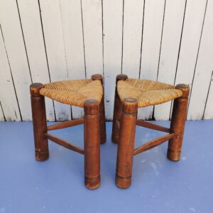 Paire de tabourets tripodes  de forme triangulaire aux pieds en bois vernis faisant penser au travail de Charles Dudouyt. Assises paillées. Traces d'usage  Bon état général. Hauteur : 37 cm Coté assise : 31 x 31 x 31 cm
