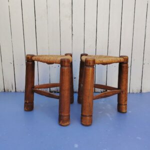 Paire de tabourets tripodes  de forme triangulaire aux pieds en bois vernis faisant penser au travail de Charles Dudouyt. Assises paillées. Traces d'usage  Bon état général. Hauteur : 37 cm Coté assise : 31 x 31 x 31 cm