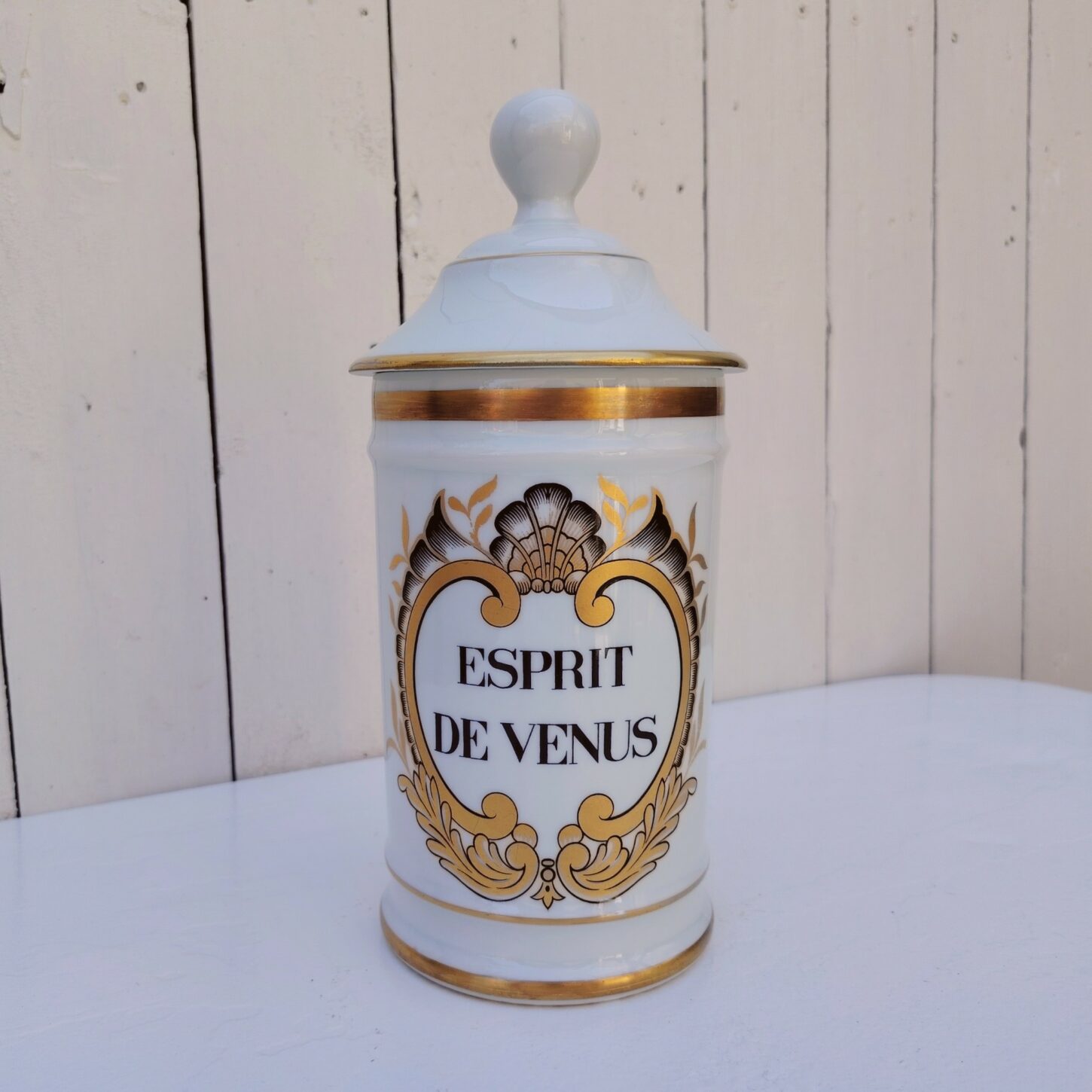 Grand pot d'apothicaire en porcelaine de Limoges.  Inscription : " Esprit de Vénus" Petit manque de  dorure sur le contour du couvercle. Très bon état Hauteur avec couvercle :  28 cm Diamètre : 11 cm