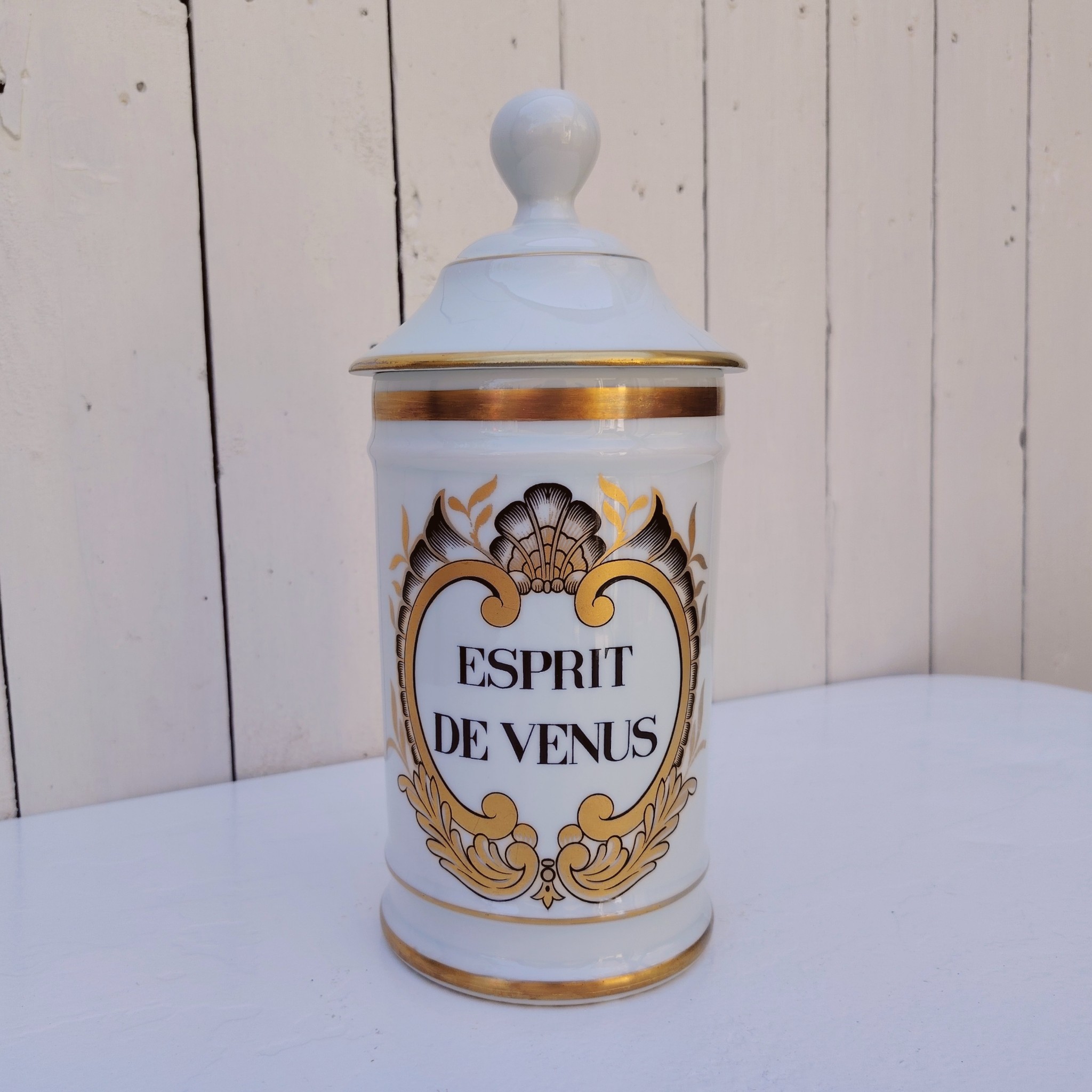 Grand pot d'apothicaire en porcelaine de Limoges.  Inscription : " Esprit de Vénus" Petit manque de  dorure sur le contour du couvercle. Très bon état Hauteur avec couvercle :  28 cm Diamètre : 11 cm