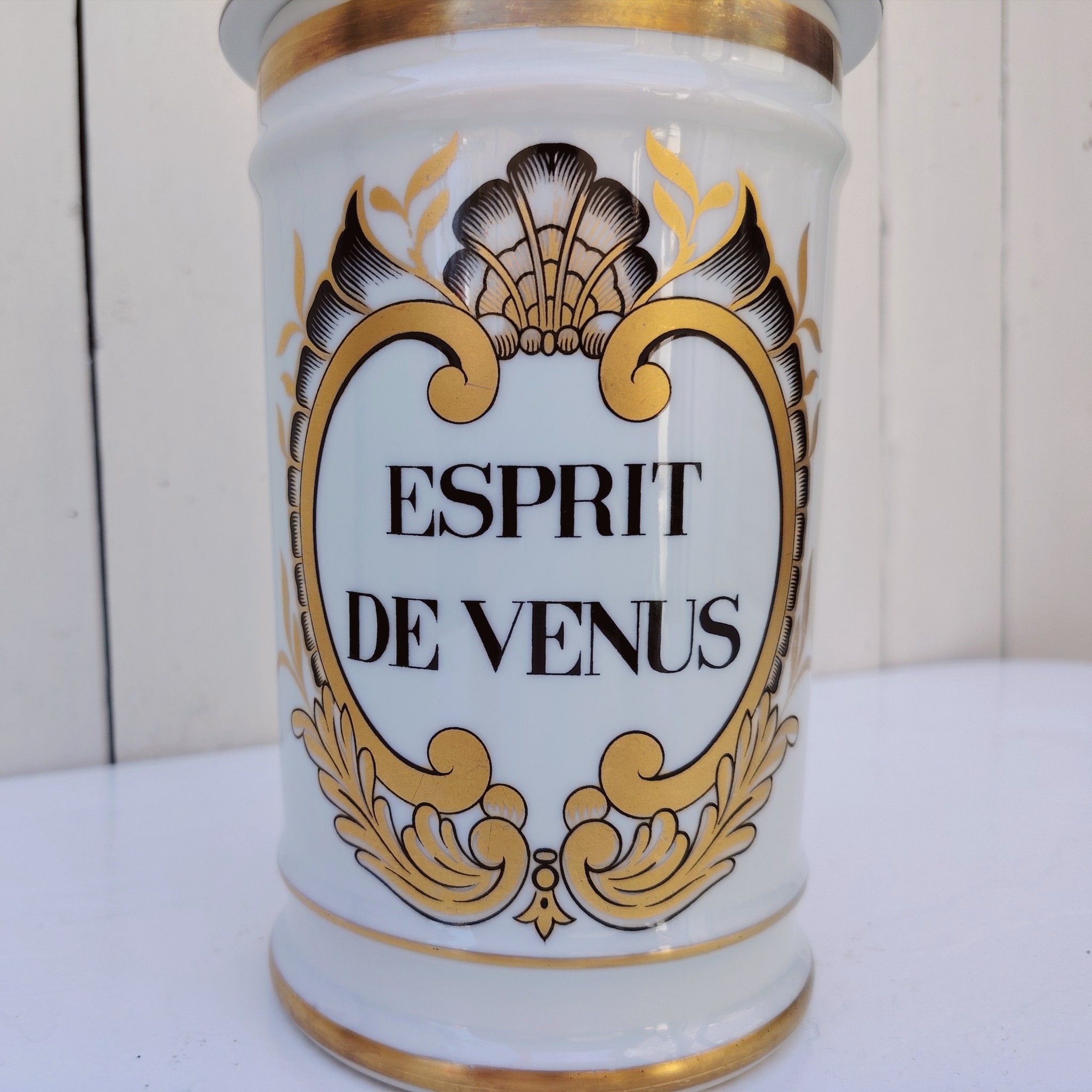 Grand pot d'apothicaire en porcelaine de Limoges.  Inscription : " Esprit de Vénus" Petit manque de  dorure sur le contour du couvercle. Très bon état Hauteur avec couvercle :  28 cm Diamètre : 11 cm
