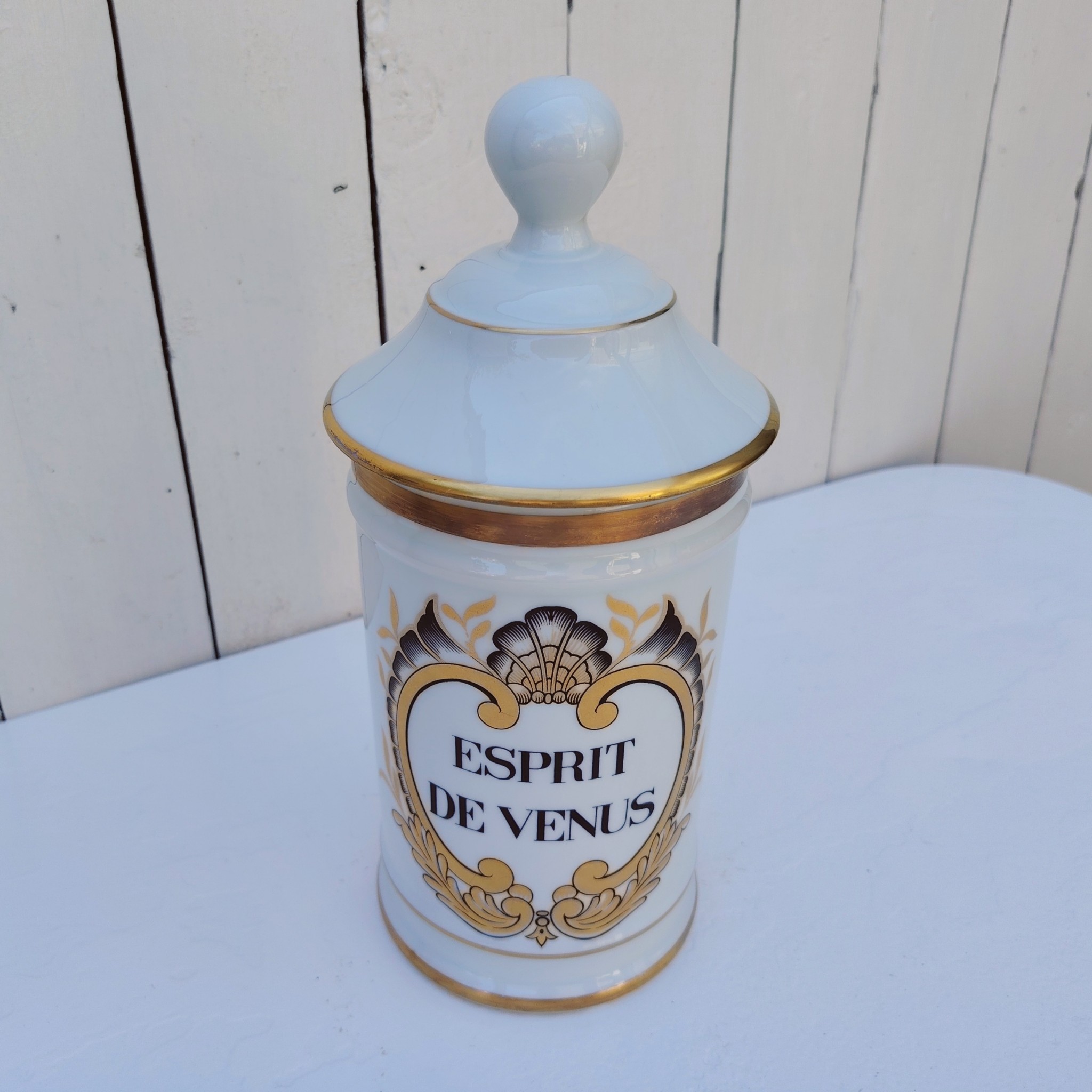 Grand pot d'apothicaire en porcelaine de Limoges.  Inscription : " Esprit de Vénus" Petit manque de  dorure sur le contour du couvercle. Très bon état Hauteur avec couvercle :  28 cm Diamètre : 11 cm