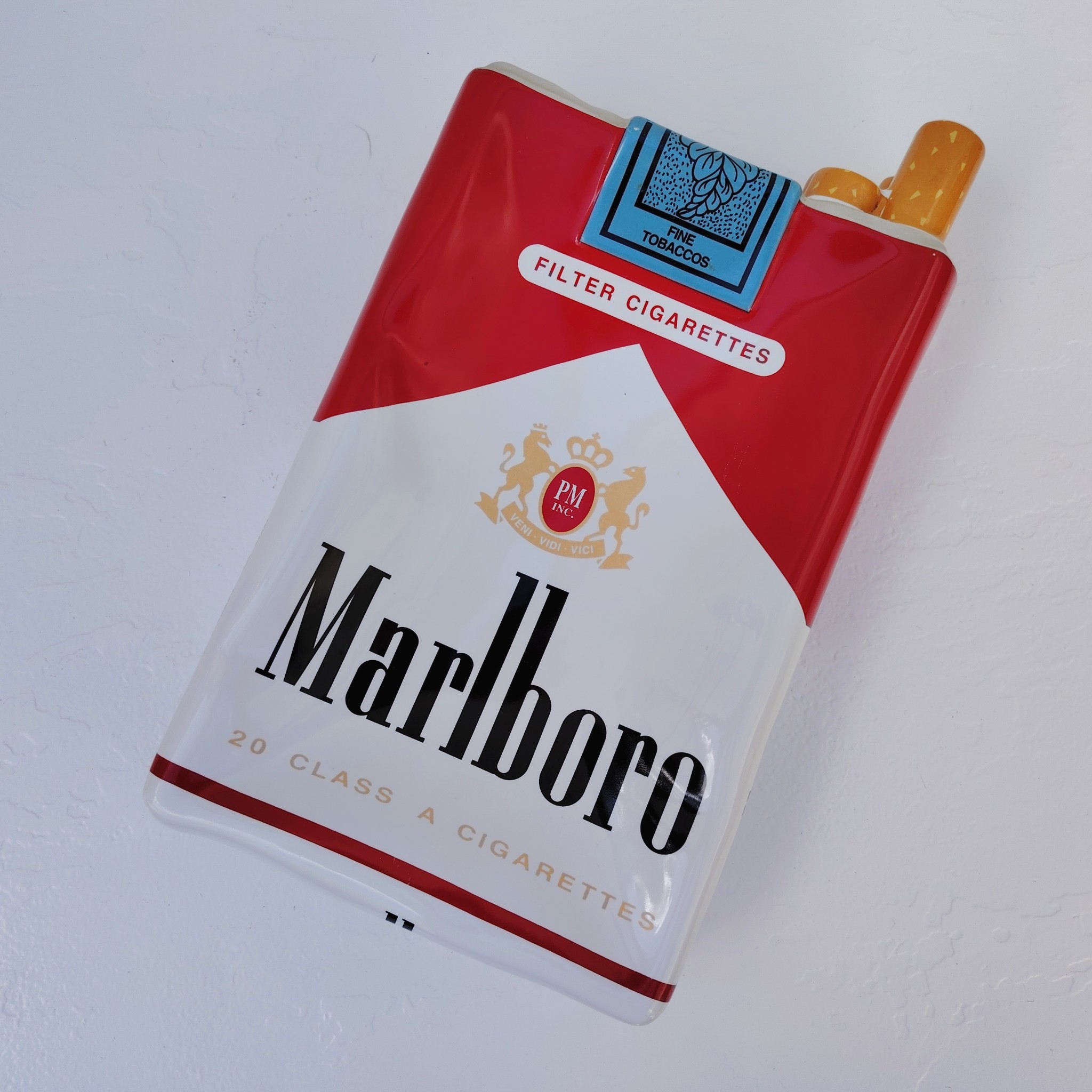 Grand vide poche en céramique représentant un paquet de cigarettes de la marque Marlboro. Petites rayures et traces d'usage sans gravité. Bon état général. Dimensions : 33 x 18 x 7 cm