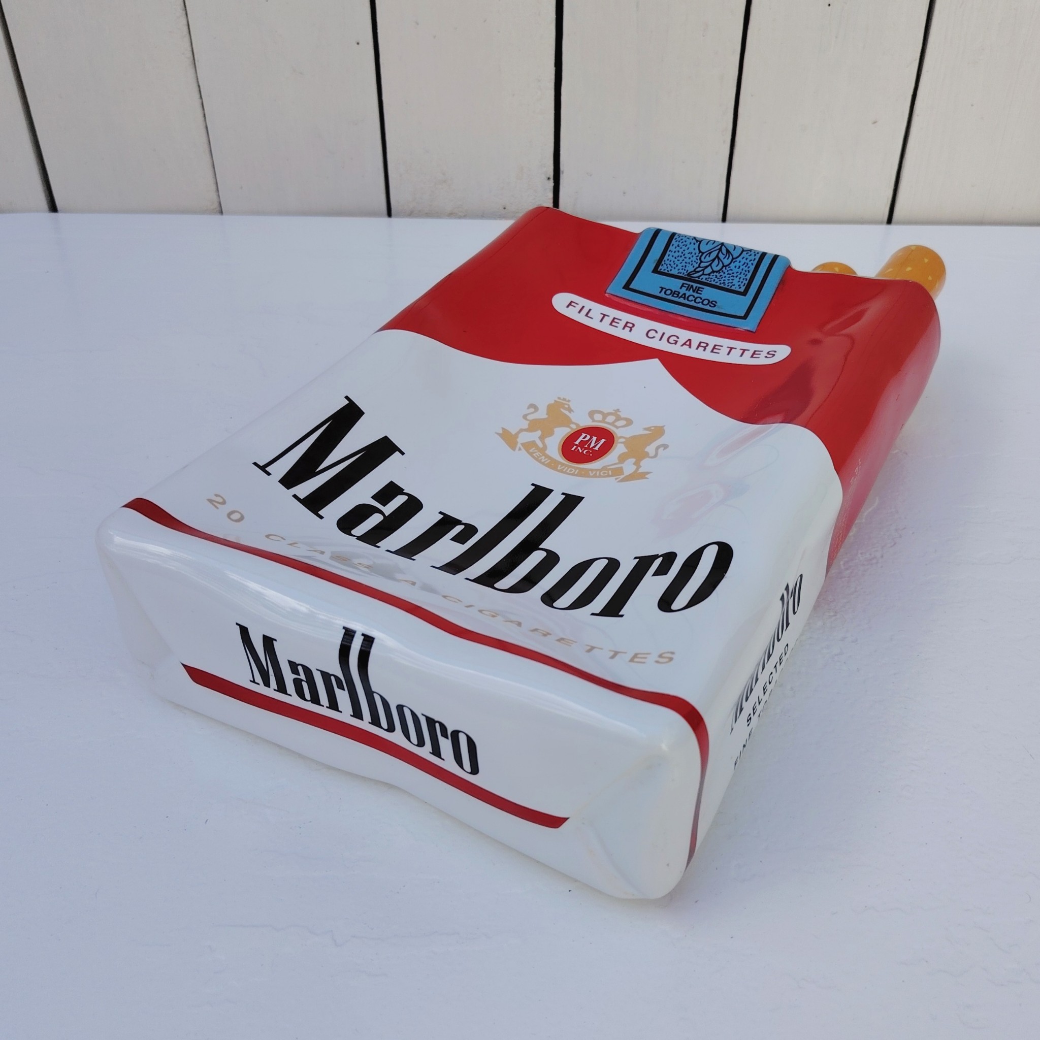 Grand vide poche en céramique représentant un paquet de cigarettes de la marque Marlboro. Petites rayures et traces d'usage sans gravité. Bon état général. Dimensions : 33 x 18 x 7 cm