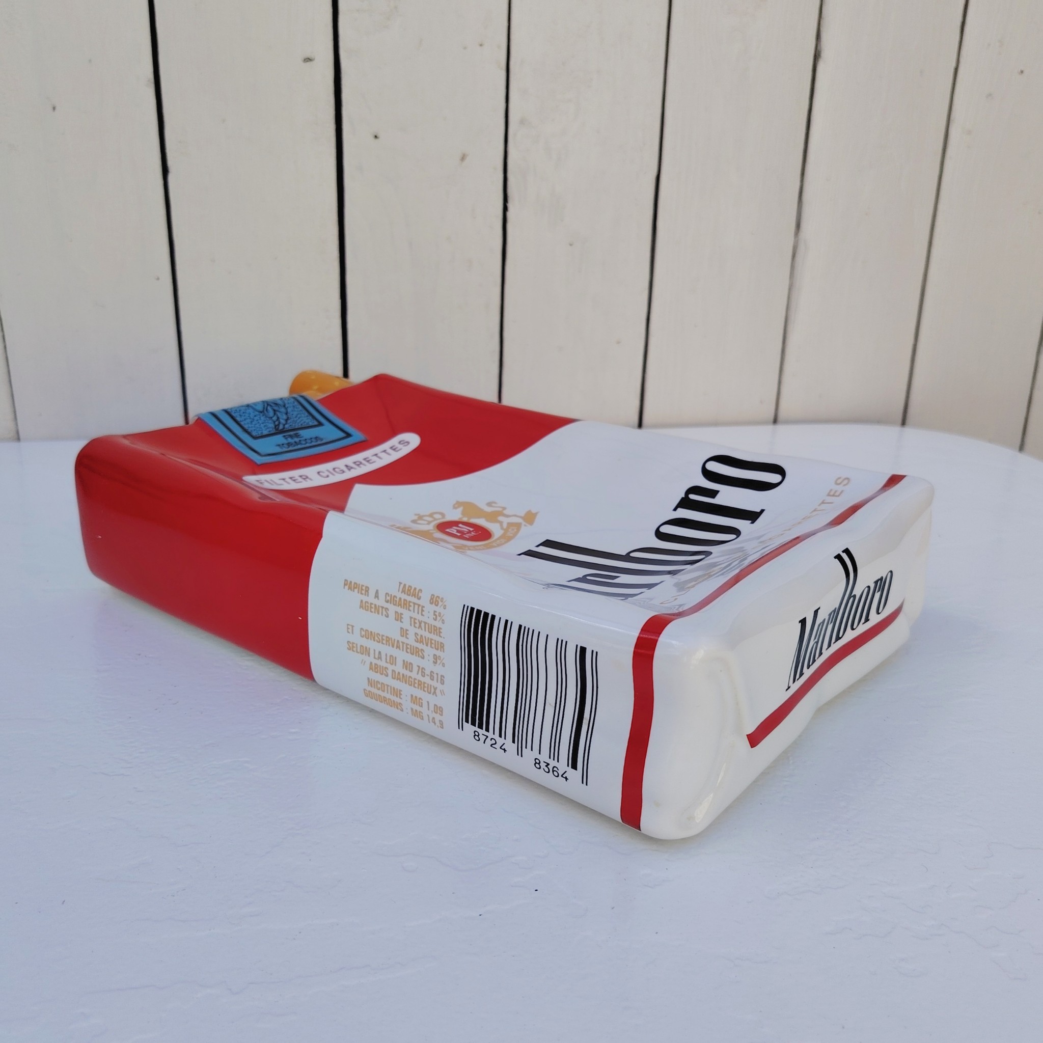 Grand vide poche en céramique représentant un paquet de cigarettes de la marque Marlboro. Petites rayures et traces d'usage sans gravité. Bon état général. Dimensions : 33 x 18 x 7 cm