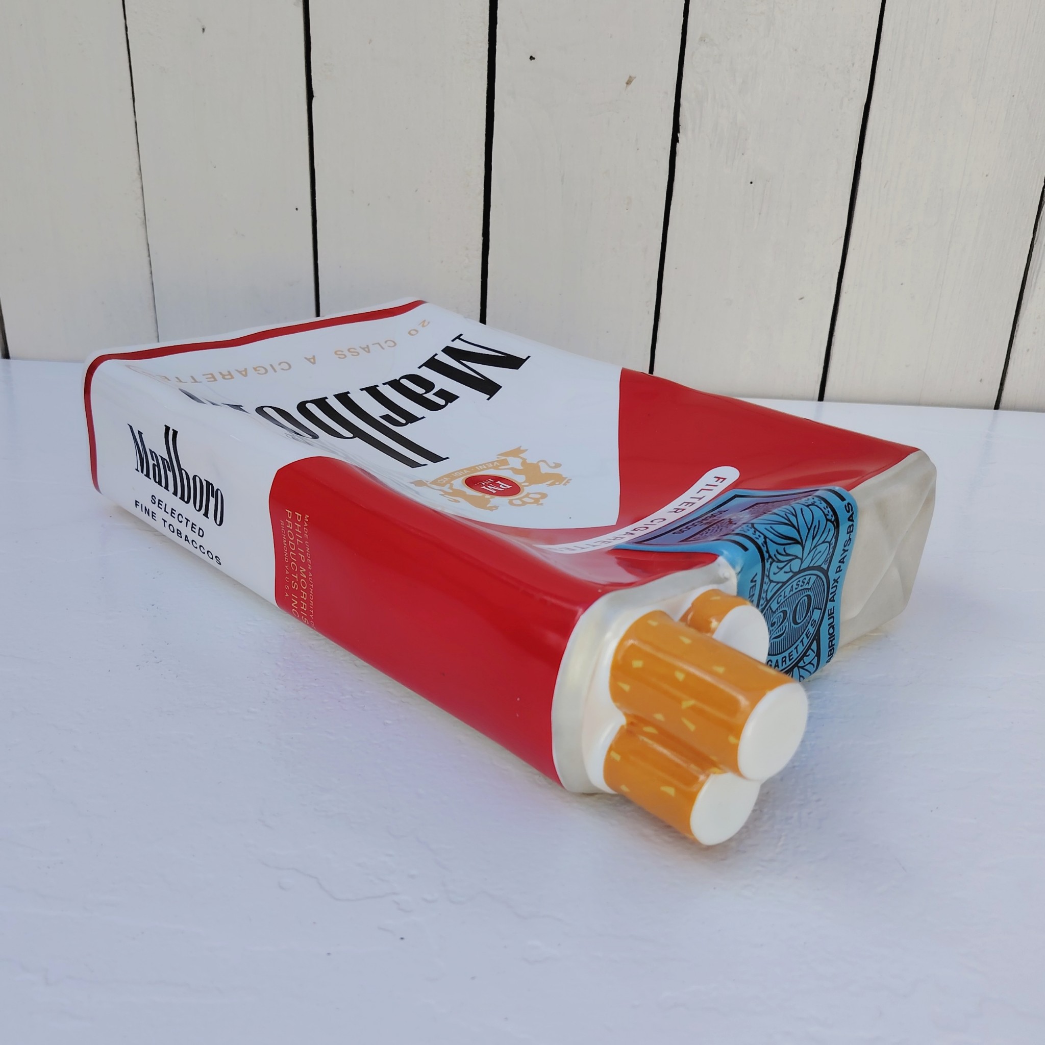 Grand vide poche en céramique représentant un paquet de cigarettes de la marque Marlboro. Petites rayures et traces d'usage sans gravité. Bon état général. Dimensions : 33 x 18 x 7 cm