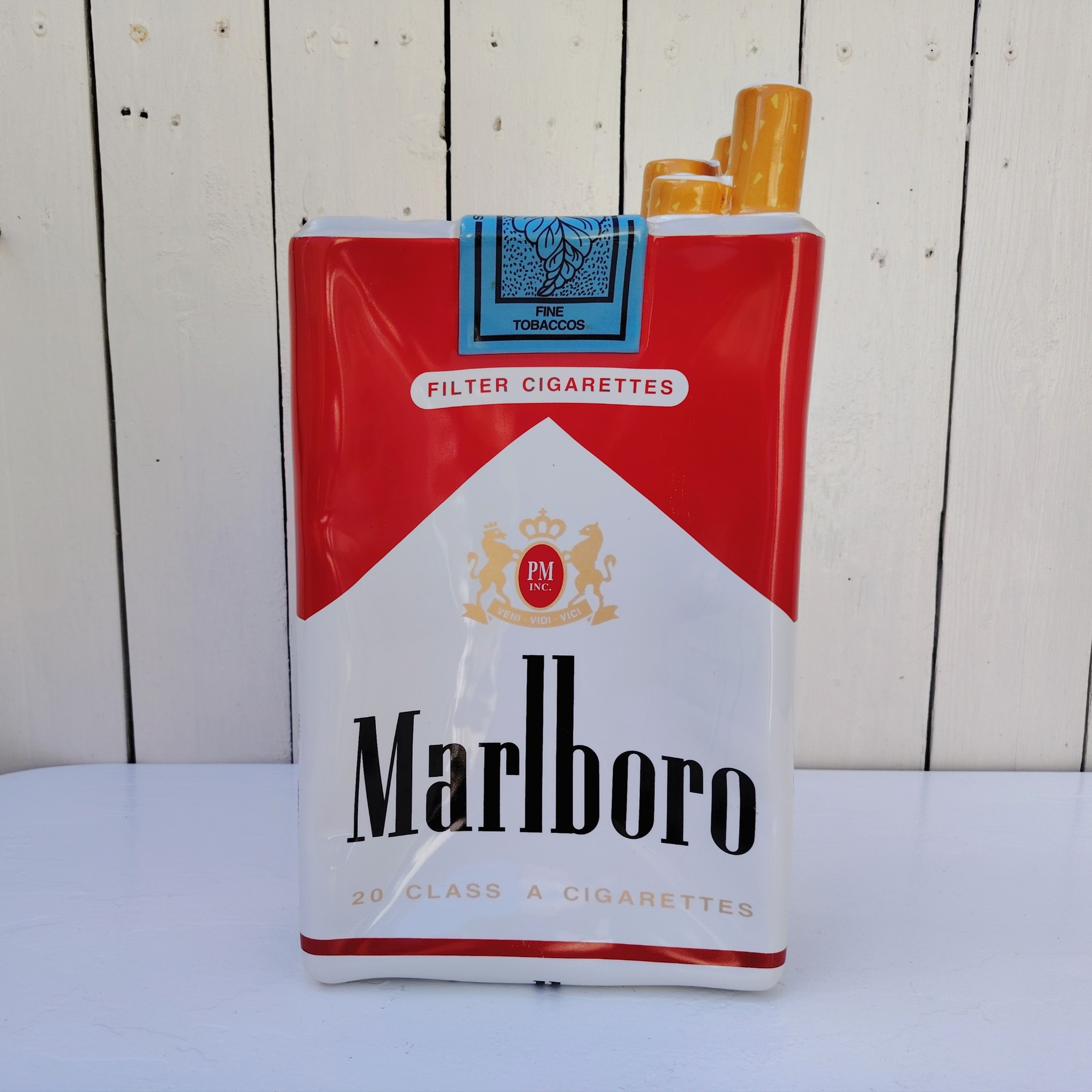 Grand vide poche en céramique représentant un paquet de cigarettes de la marque Marlboro. Petites rayures et traces d'usage sans gravité. Bon état général. Dimensions : 33 x 18 x 7 cm