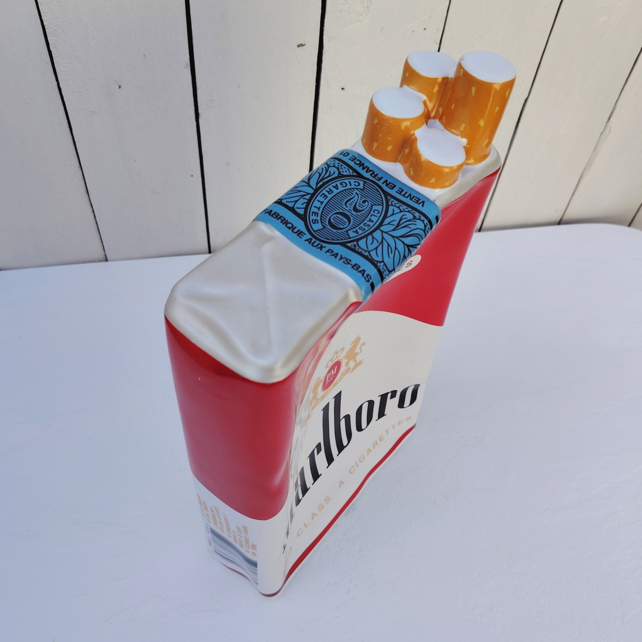Grand vide poche en céramique représentant un paquet de cigarettes de la marque Marlboro. Petites rayures et traces d'usage sans gravité. Bon état général. Dimensions : 33 x 18 x 7 cm