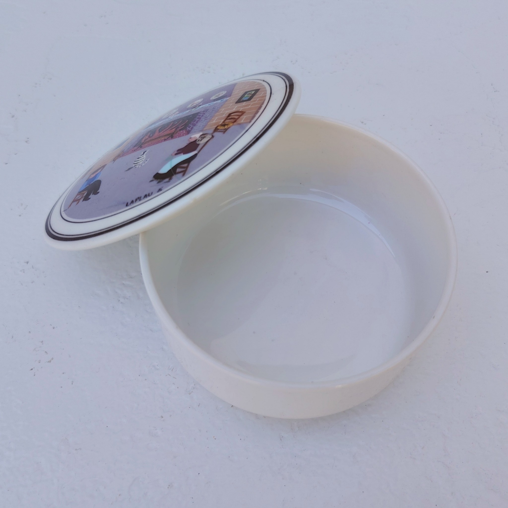 Boite en porcelaine Villeroy & Boch, décor naïf par Laplau. Décor d'un couple au coin du feu. Excellent état. Hauteur : 5 cm Diamètre : 10,5 cm