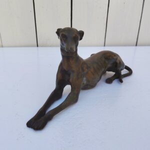 Sculpture en bronze représentant un lévrier en position du sphinx, belle patine mordorée. Belle définition des détails. Traces d'usage Bon état général . Dimensions : 23 x 7 x 10 cm