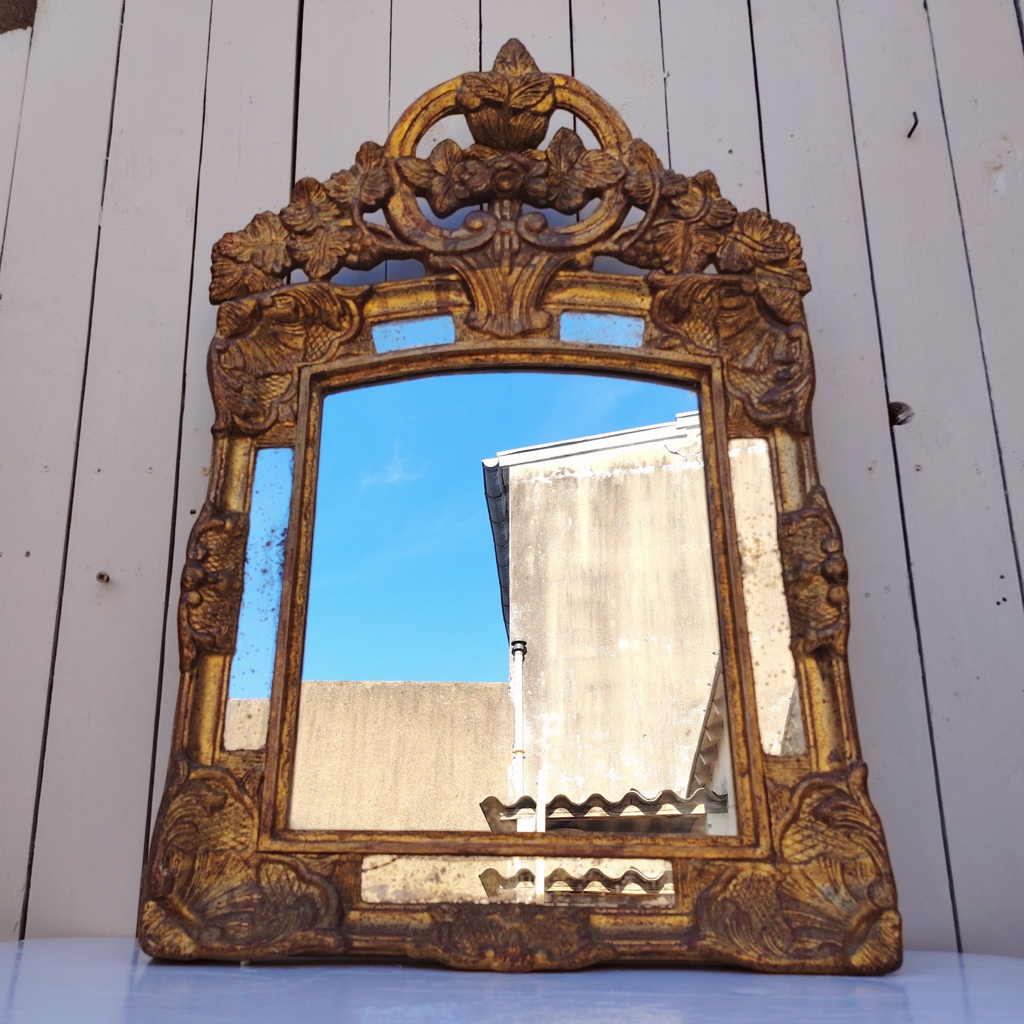 Miroir italien reproduisant de style régence, en bois doré et parcloses. Epoque XXème. Piqûre des tains des parcloses. manque de dorures. Bon état général 81 x 53 cm