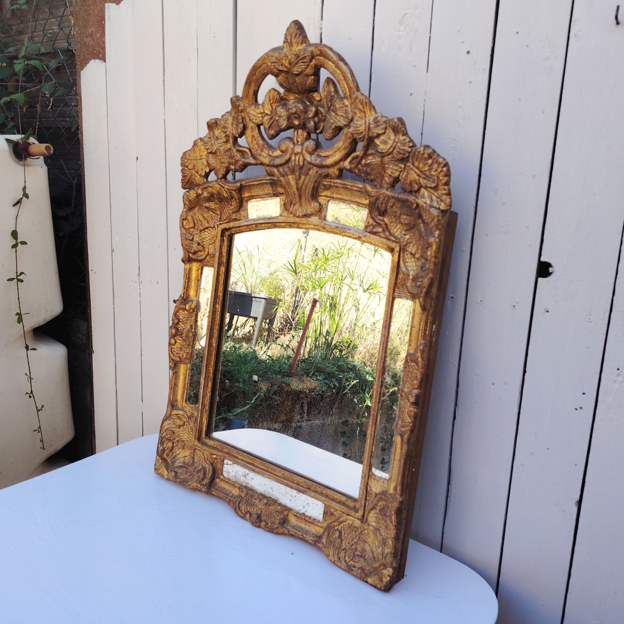 Miroir italien reproduisant de style régence, en bois doré et parcloses. Epoque XXème. Piqûre des tains des parcloses. manque de dorures. Bon état général 81 x 53 cm