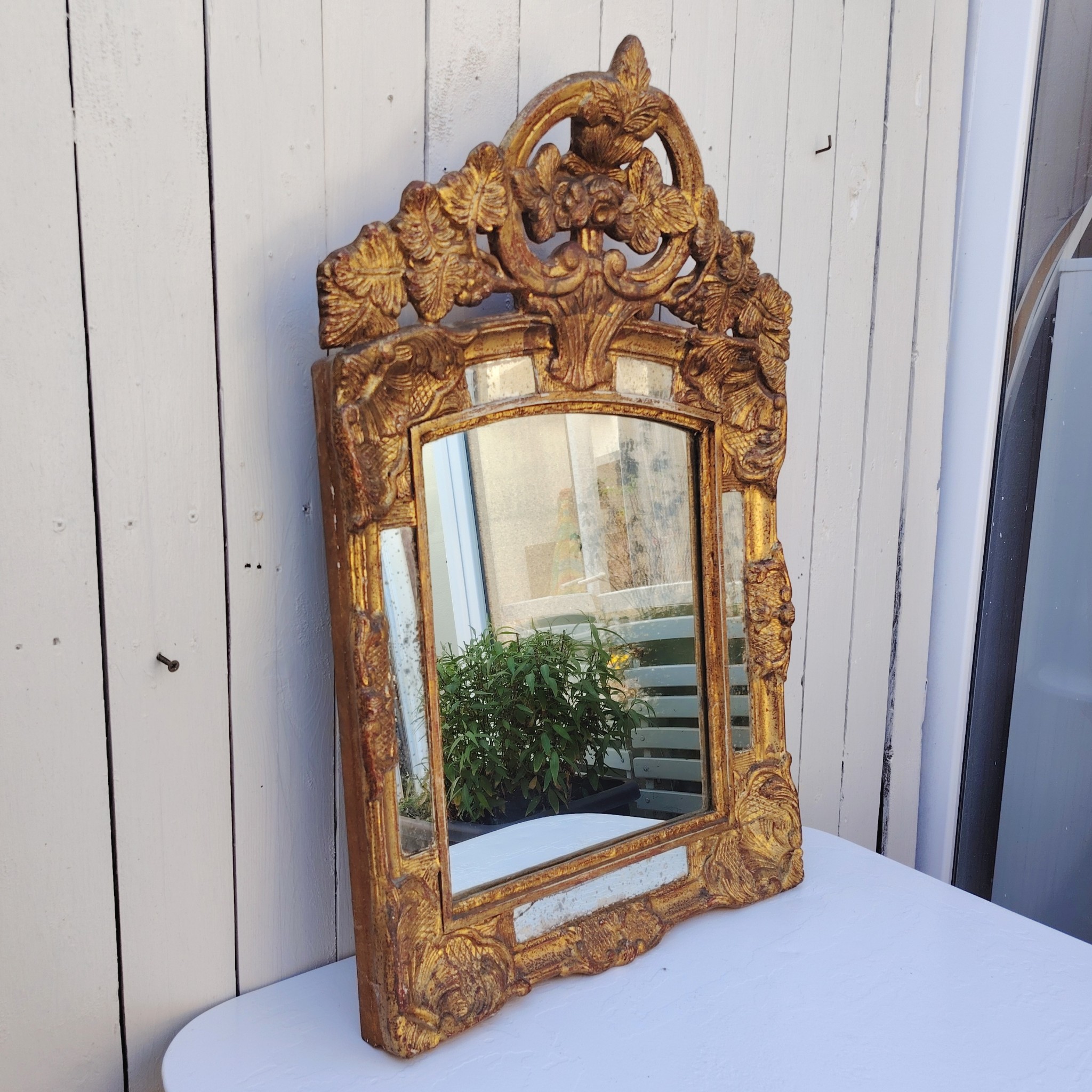Miroir italien reproduisant de style régence, en bois doré et parcloses. Epoque XXème. Piqûre des tains des parcloses. manque de dorures. Bon état général 81 x 53 cm